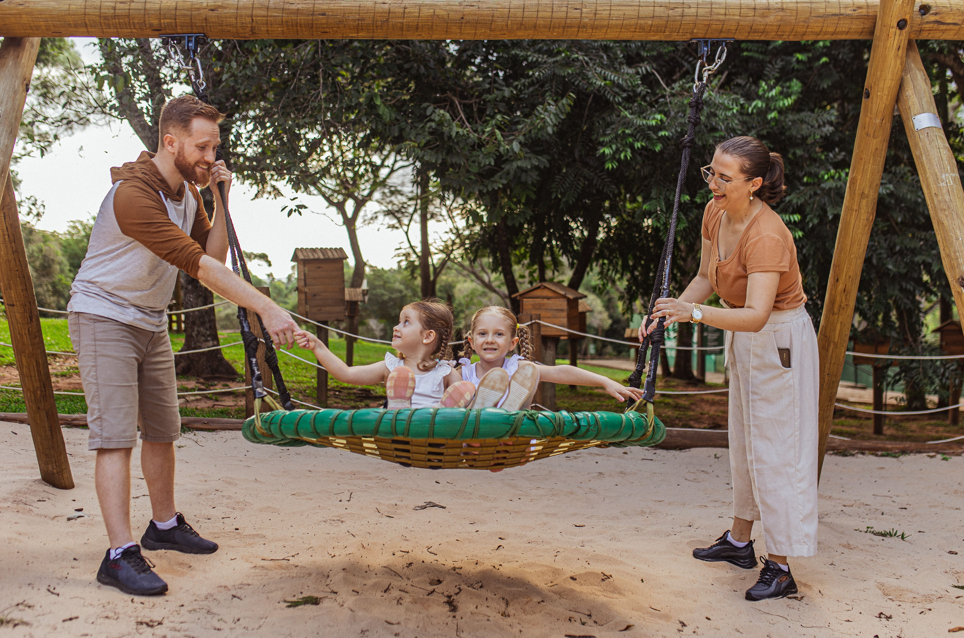 Pai e mãe brincando com as filhas em um balanço